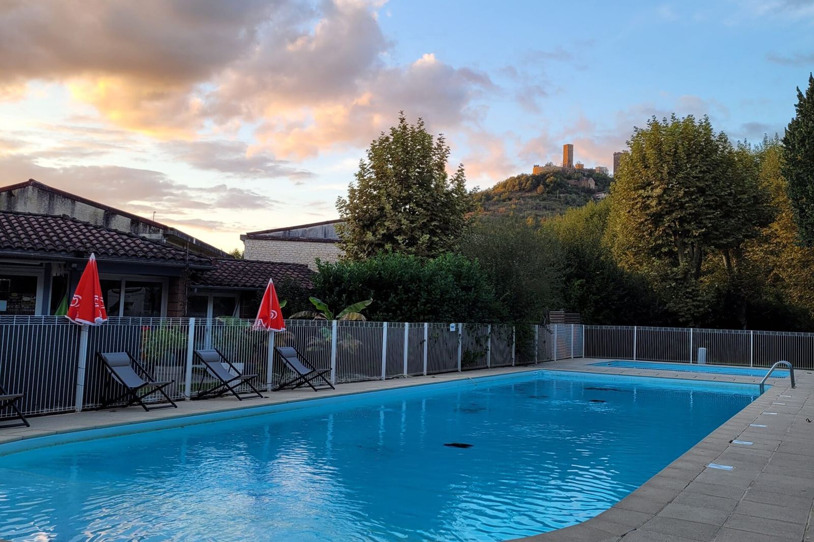 La piscine du Camping Le Soulhol au coucher du soleil, face aux Tours de Saint-Laurent